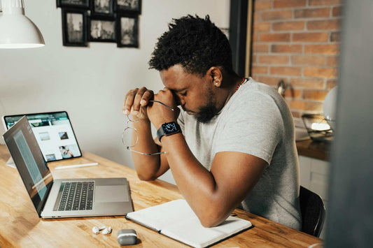 Man rubbing his eyes in front of computer