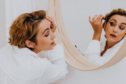 Woman fixing eye makeup in mirror