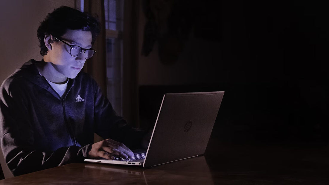 Man looking at laptop in dark with glasses on